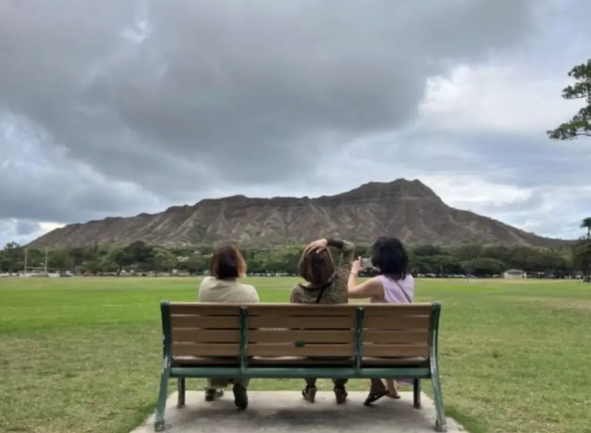 ベンチに座ってダイヤモンドヘッドを眺める人々の風景。ハワイ初心者におすすめの観光スポット。