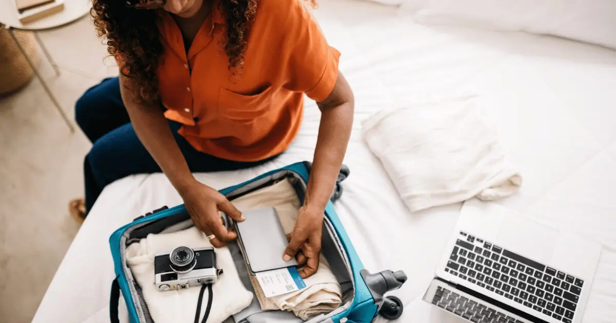 A senior traveler packing a suitcase with essential items for a Hawaii trip, including a camera, passport, and travel documents.